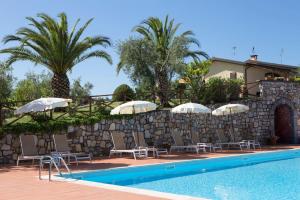 a pool with chairs and umbrellas next to a stone wall at Agriturismo La Cipriana in Castagneto Carducci +24 photos