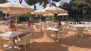 a man and woman sitting at tables in a restaurant at Leman Hotel y Apartamentos in Playa de Palma