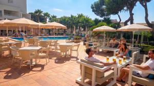 a group of people sitting at tables near a pool at Leman Hotel y Apartamentos in Playa de Palma +73 photos