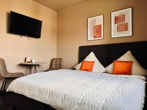 a bedroom with a bed with orange pillows and a flat screen tv at BASE stay Erlangen in Erlangen