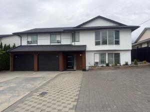 a white house with a garage and a driveway at J & J Dream Villa Ltd in Abbotsford