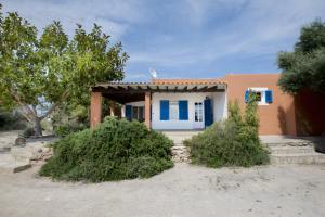 a small house with blue shutters on it at Casa Rita in San Ferrán de ses Roques
