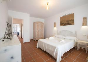 a white bedroom with a white bed and a table at Casa Rita in San Ferrán de ses Roques