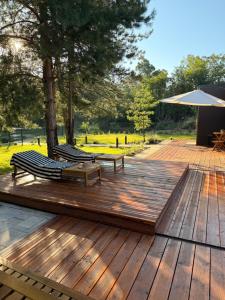 a wooden deck with two benches and an umbrella at Villa Ruj Retreat Deliblatska Peščara in Šumarak