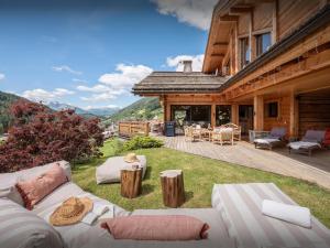 an outdoor patio with couches and tables on a house at Chalet Alti - OVO Network in Le Grand-Bornand
