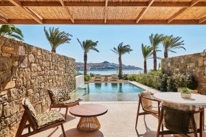 a patio with a table and chairs and a pool at Fouquet's Mykonos in Mikonos