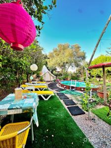 a garden with tables and chairs and a pink umbrella at Bell Tent Lovers by Casa das Artes in Luz de Tavira +25 photos
