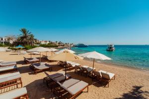 a beach with chairs and umbrellas and the ocean at Aqua Fun Resort in Hurghada