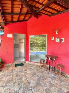 a red room with a table and two stools at Pousada Jardim do Éden in Serra do Cipo