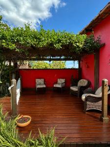 a wooden deck with chairs and a red wall at Pousada Jardim do Éden in Serra do Cipo