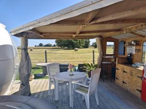 a patio with a table and chairs on a deck at La chevauchée vers les étoiles in Yèvres
