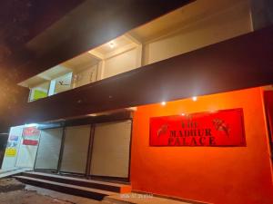 a building with an orange wall with a sign on it at Hotel Madhur Palace in Bhopal