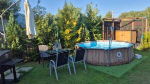 a hot tub in a yard with chairs and an umbrella at Domek Adam - Jacuzzi dodatkowo płatne in Kościerzyna