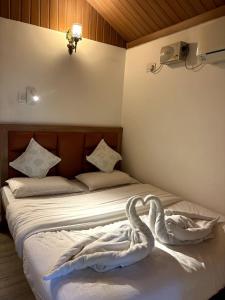 a bedroom with a bed with two swans on it at Rimzim's Tatvamasi - A Pool Villa Retreat in Kudāl +50 photos