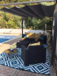 a patio with couches and an umbrella next to a pool at Les Menendos in Saint-Jean-de-Barrou