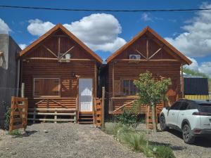 a log cabin with a car parked in front of it at Cabañas Ruidos de Agua in Choele Choel