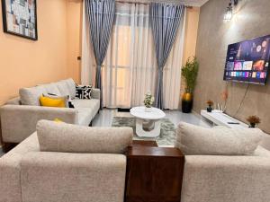 a living room with two couches and a tv at Mallony Homes in Kampala