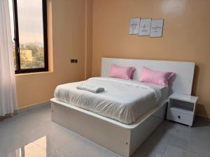 a bedroom with a bed with pink pillows and a window at Mallony Homes in Kampala