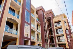 a tall building with cars parked in front of it at Mallony Homes in Kampala