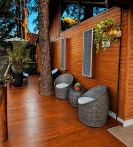 a porch with two wicker chairs and a tree at Chalé Veraneio-Itú-SP Vista para o lago Camping Carrion in Itu