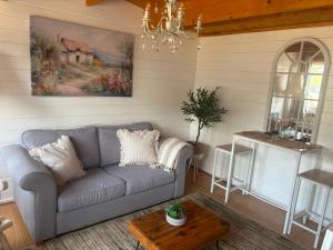 a living room with a couch and a table at Modern Cabin with large private garden in Old Romney