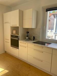 a kitchen with white cabinets and a sink and a window at Historic Charm Apartment Bayreuth in Bayreuth +7 photos