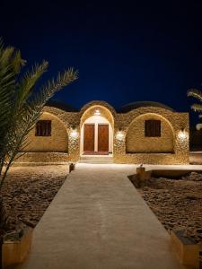 a building with a pathway leading to a door at night at Cafour House Siwa - Hot Spring in Siwa