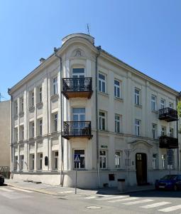 a large white building with balconies on a street at Apartament Verde Stare Miasto in Chełm