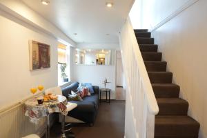 a living room with a blue couch and stairs at Cosy 3BR House, 2 Bath, Near Luton Centre in Luton