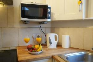 a kitchen counter with a bowl of fruit and two glasses of orange juice at Cosy 3BR House, 2 Bath, Near Luton Centre in Luton