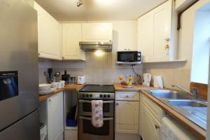 a kitchen with white cabinets and a stove and a sink at Cosy 3BR House, 2 Bath, Near Luton Centre in Luton +8 photos