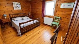 a bedroom with a bed and a green chair at Le chalet du mazagran in Leffincourt