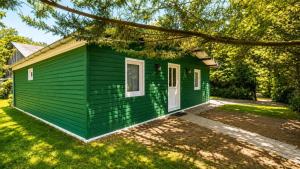 a green tiny house in a yard at Le chalet du mazagran in Leffincourt +6 photos