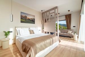 a white bedroom with a large bed and a couch at Balsamia Boutique Apartments in Podčetrtek