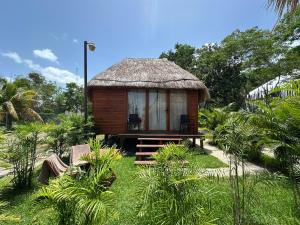 a small hut with a grass roof in a garden at GlampCalar lagoon Front Bungalows in Rancho Bacalar
