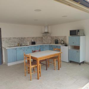 a kitchen with a wooden table and blue cabinets at Grand Fonteneau in Saint-Romain