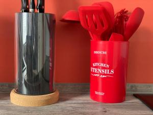 a kitchen utensils in a red cup on a table at Ferienhaus BellaVita - mit großem eingezäuntem Garten - Infrarotsauna - 3 Hunde willkommen - Badesee 800m entfernt in Walkenried