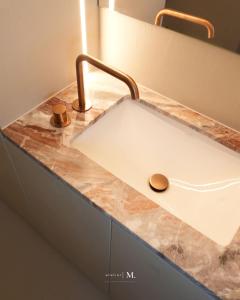 a bathroom sink with a copper faucet at Atelier M in Kruisem