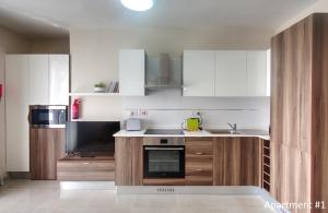 una cocina con gabinetes blancos y un horno con placa de cocina en Marbella Holiday Apartments - Seafront - Wifi, en Marsaskala