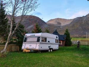 a white caravan parked in a yard next to a house at Stetind Skicamp in Lyngen