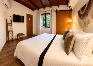 a bedroom with a white bed and a television at Luum Guest House Manila in Medellín