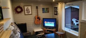 a room with a television and a guitar on the wall at Stetind Skicamp in Lyngen