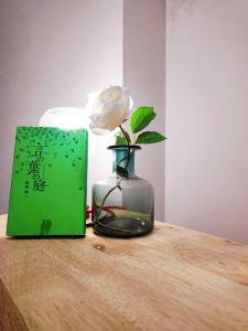 a rose in a vase on a table with a book at Toyo Yoyoginumi in Tokyo