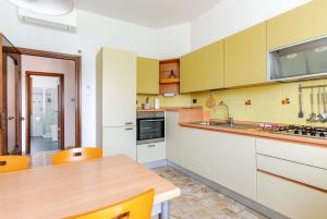 a kitchen with white cabinets and a wooden table at Apartment Superiore a 950 metri dal mare in Albisola Superiore