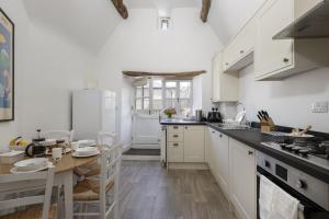 a kitchen with white cabinets and a wooden table at The Haven in Chipping Norton +20 photos