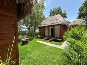 a small hut with a grass roof and a bench at GlampCalar lagoon Front Bungalows in Rancho Bacalar