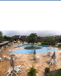 a swimming pool with chairs and umbrellas in a resort at Flat 705 Winterville - Gravatá in Gravatá