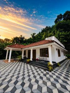 a small white house with a checkered floor at Mist & Meadows Premium VIlla By STAYVA in Munnar