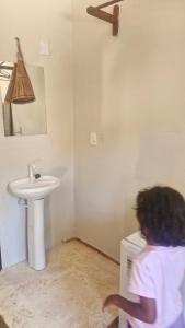 a woman is standing in a bathroom with a sink at Suíte privada in Jericoacoara