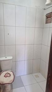 a white tiled bathroom with a toilet and a shower at Suíte privada in Jericoacoara